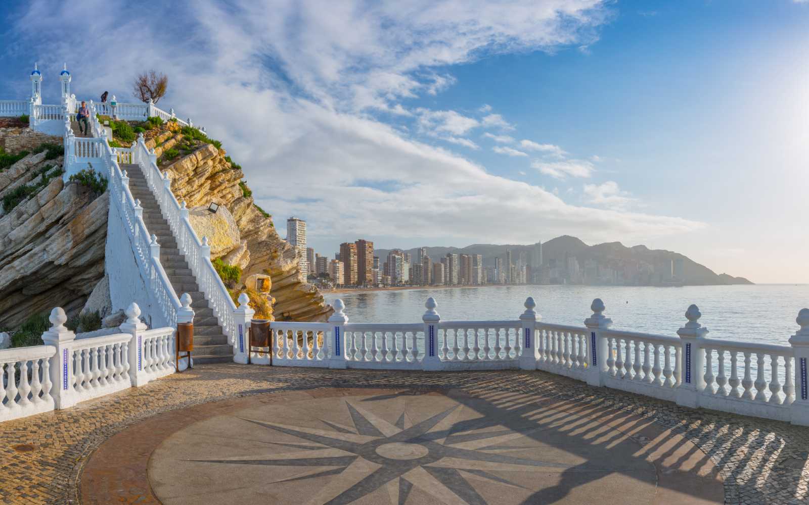 ?anoramic seascape view on beach and skyscrapers from observation deck so-called "Balcon del Mediterraneo" with white balustrade and makeshift compass on the floor. Costa Blanca. Benidorm, Spain. 