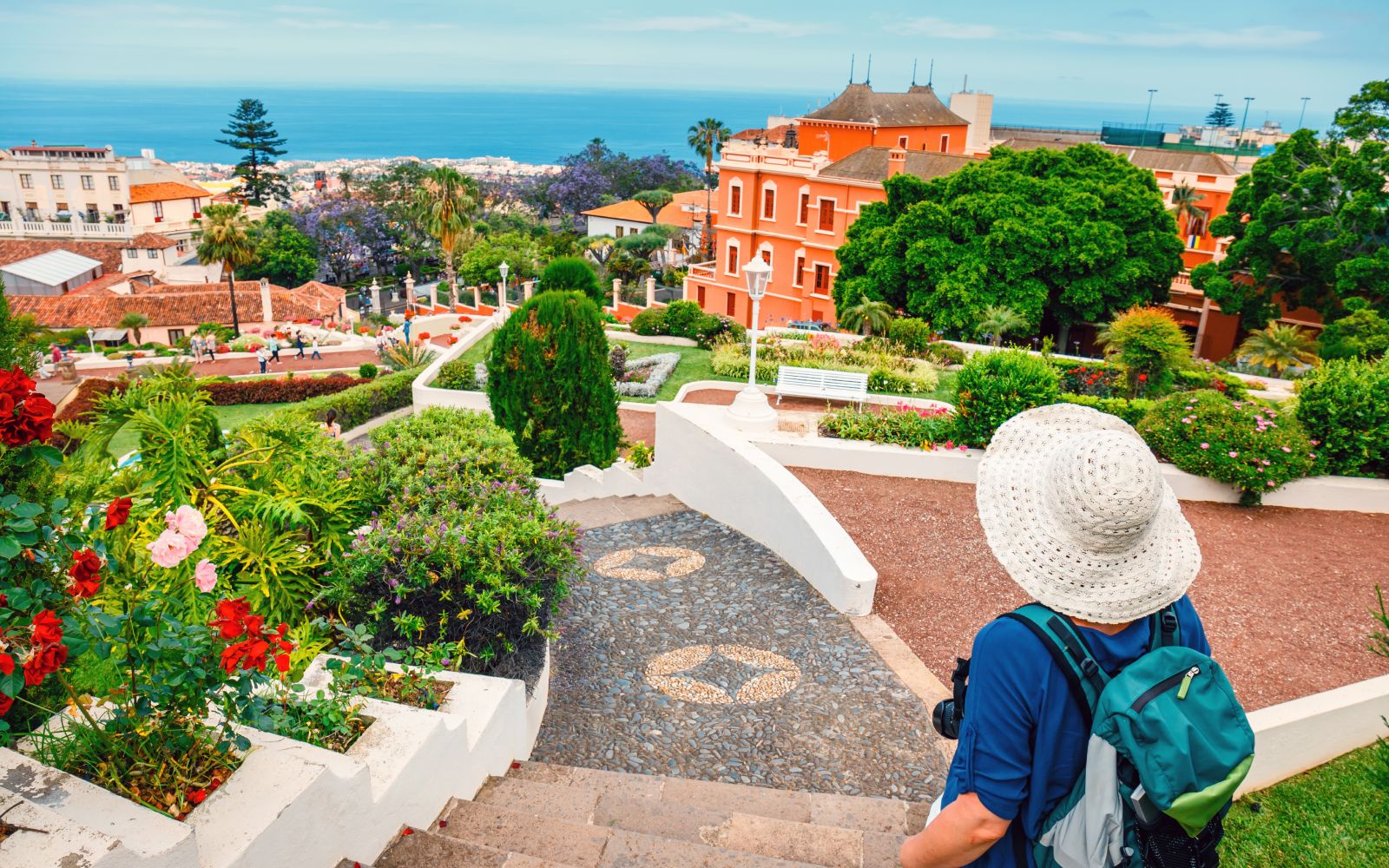 Back view of female tourist with backpack admires view of La Orotava, Spain